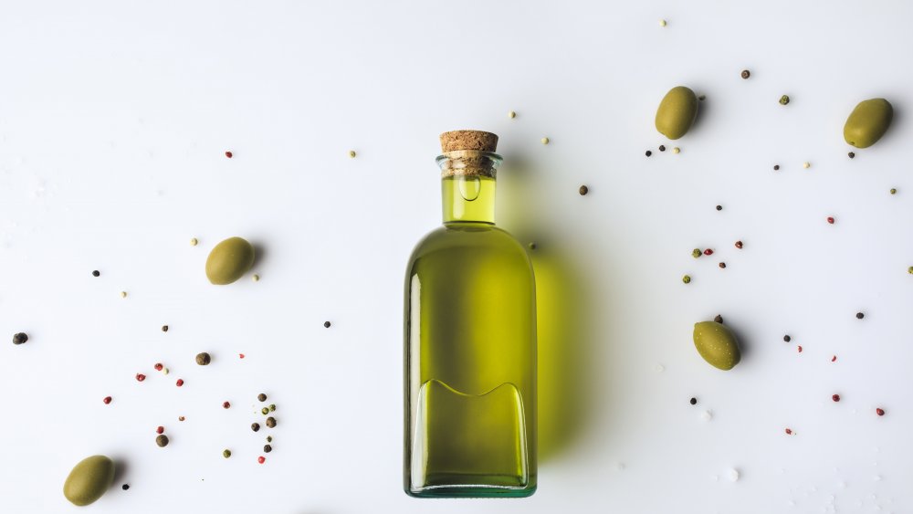 оливковое масло в окружении оливок на белом фоне