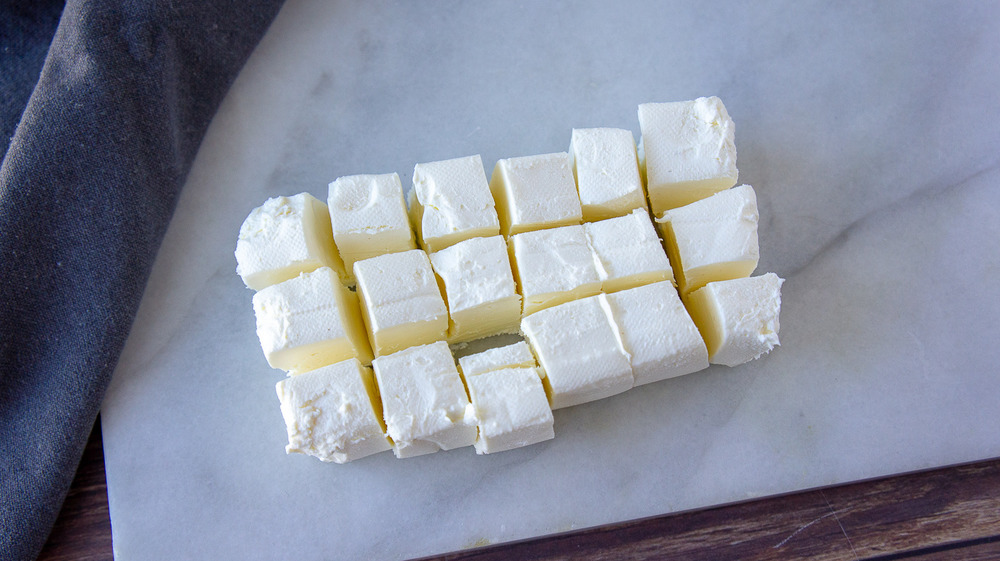 блок сливочного сыра, нарезанный на маленькие квадратики