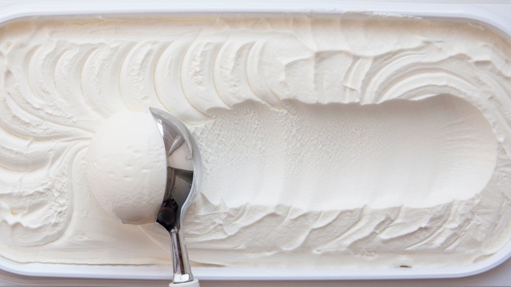 Картонная коробка ванильного мороженого с шариком, протащенным через верх