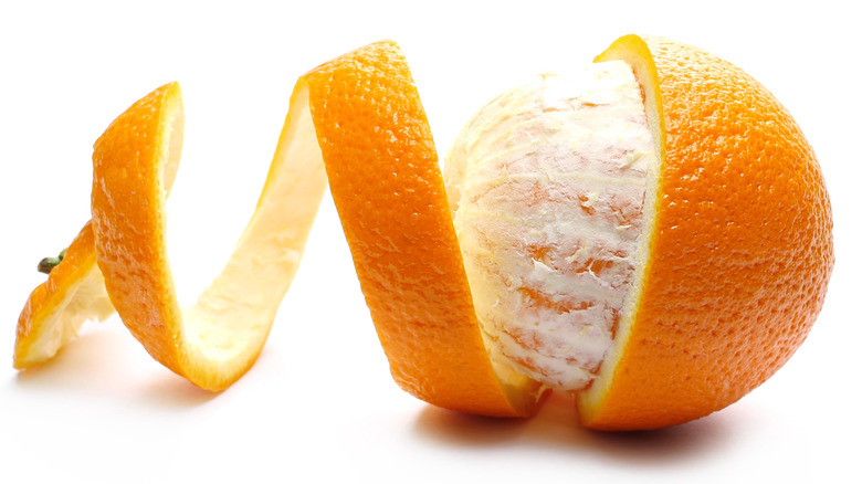 Сырой апельсин в окружении скрученной кожуры