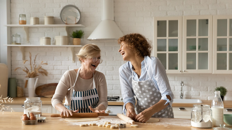 две женщины раскатывают тесто и смеются