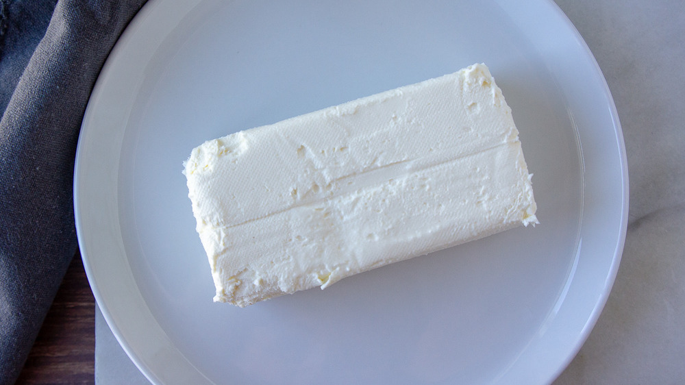 блок сливочного сыра на белой тарелке