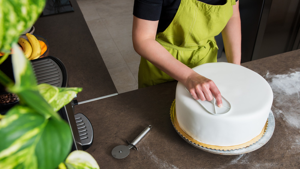 Пекарь украшает свадебный торт белой помадкой