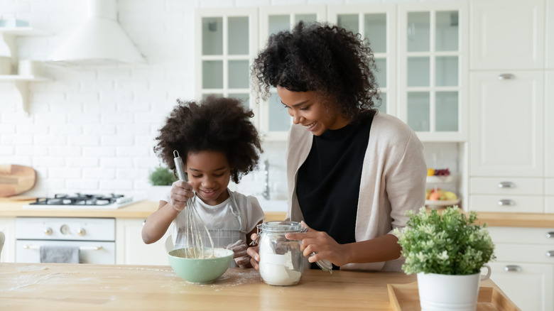 Женщина и молодая девушка замешивают тесто на кухне