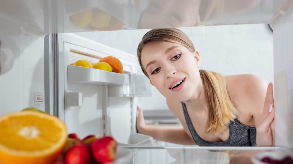 женщина осматривает свой чистый холодильник