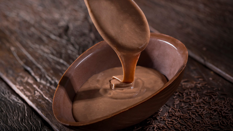 Растопленный шоколад переливается из ложки в миску